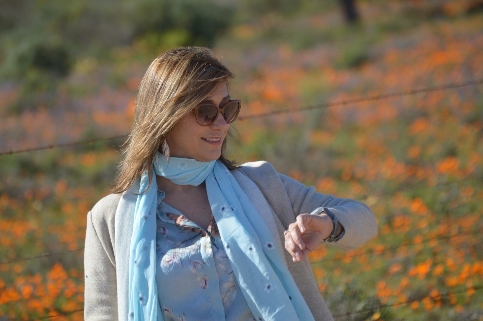 Livia Karsten checking one of her watches in a field of orange Namaqualand wildflowers